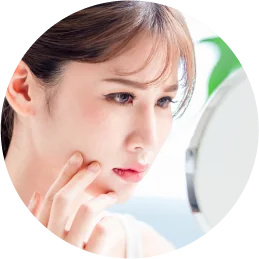 鏡を見ながら頬に触れる女性の顔